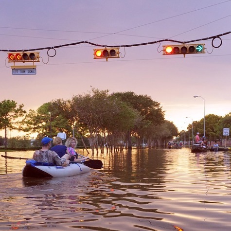 Community members in kayak in a river of high water levels that highlight flood‑risk conditions